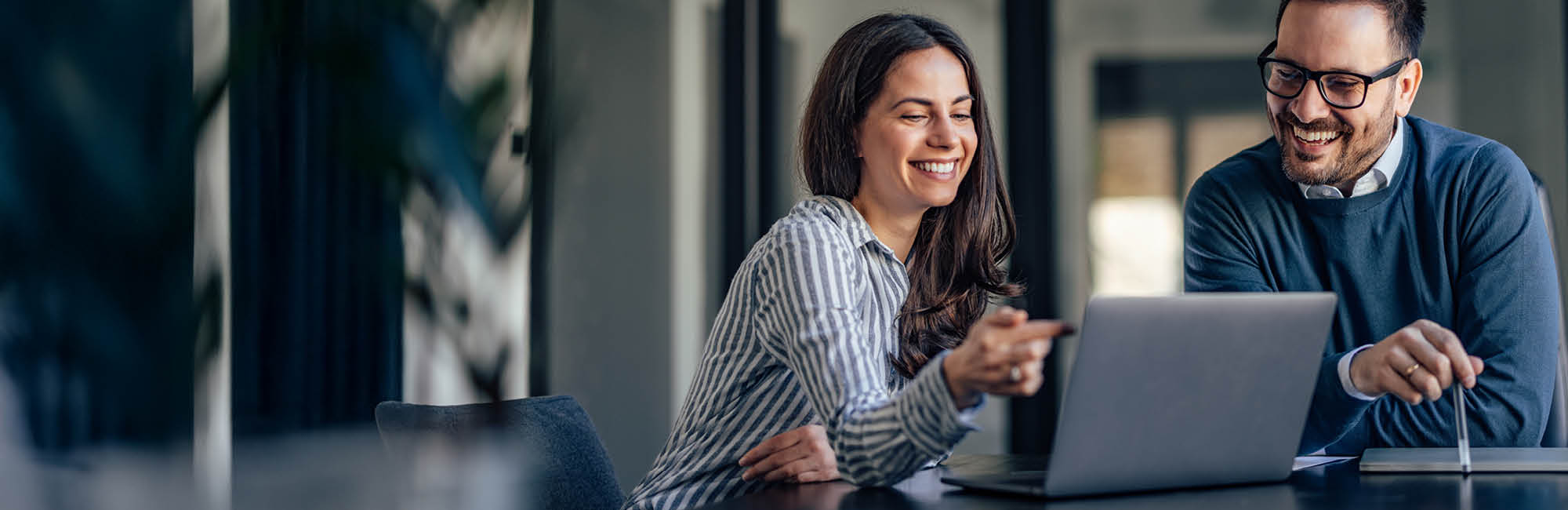 Paar sitzt vor dem Laptop und betrachtet den Monitor