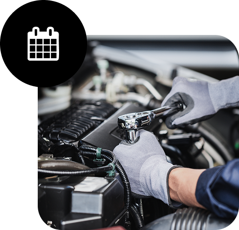 KFZ Mechaniker schraubt am Motor eines Fahrzeugs