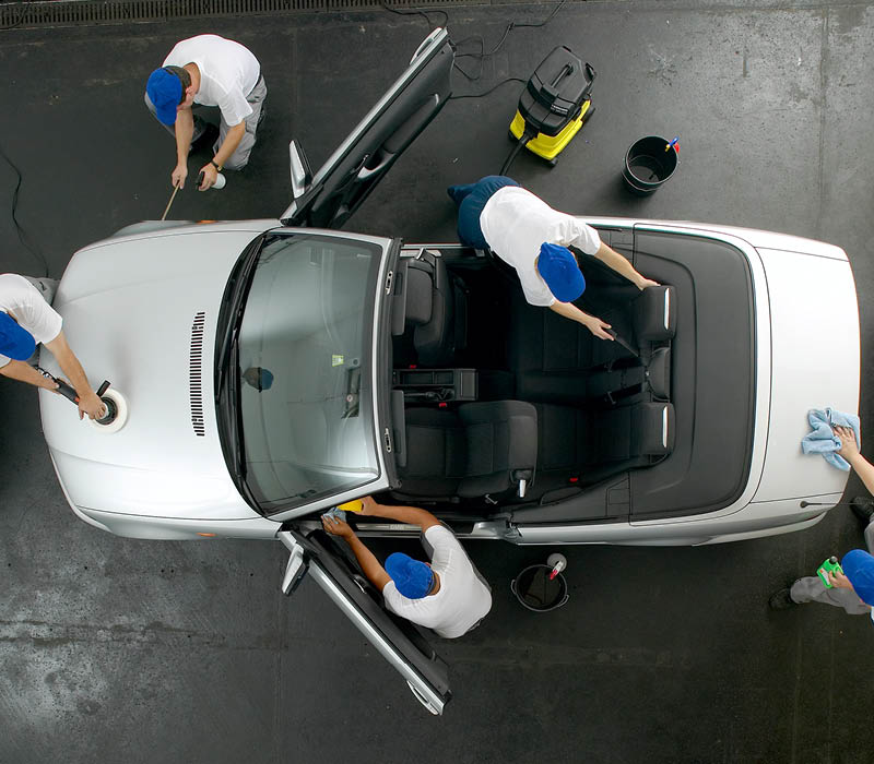 Auto wird von mehreren Mitarbeitern aufbereitet